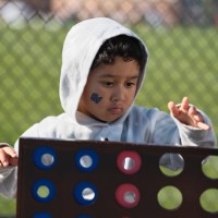 Little boy with GV tattoo on cheek playing connect four